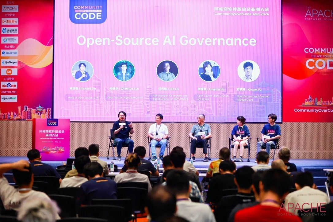 A five-person panel on Open-Source AI Governance at CommunityOverCode Asia 2024, seated on stage in front of a full room; I am at the far left, holding the microphone.