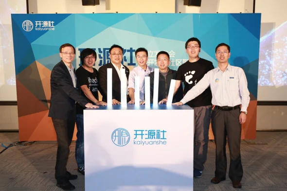 Seven people standing behind a podium bearing the KAIYUANSHE logo at the organization's founding ceremony, each with a hand resting on a lit launch column.
